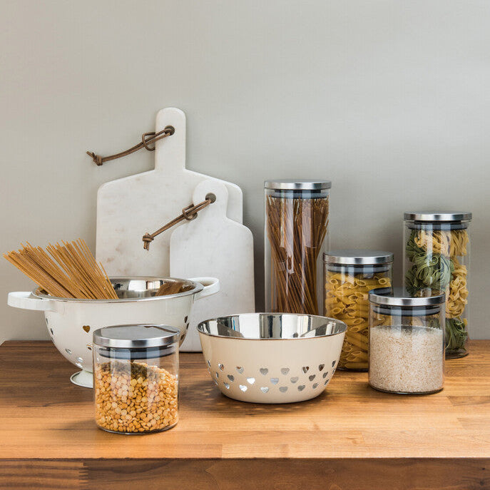 Cream-colored ceramic bowl with heart cutouts and metallic rim next to freska glass storage jar with silver lid 550ml