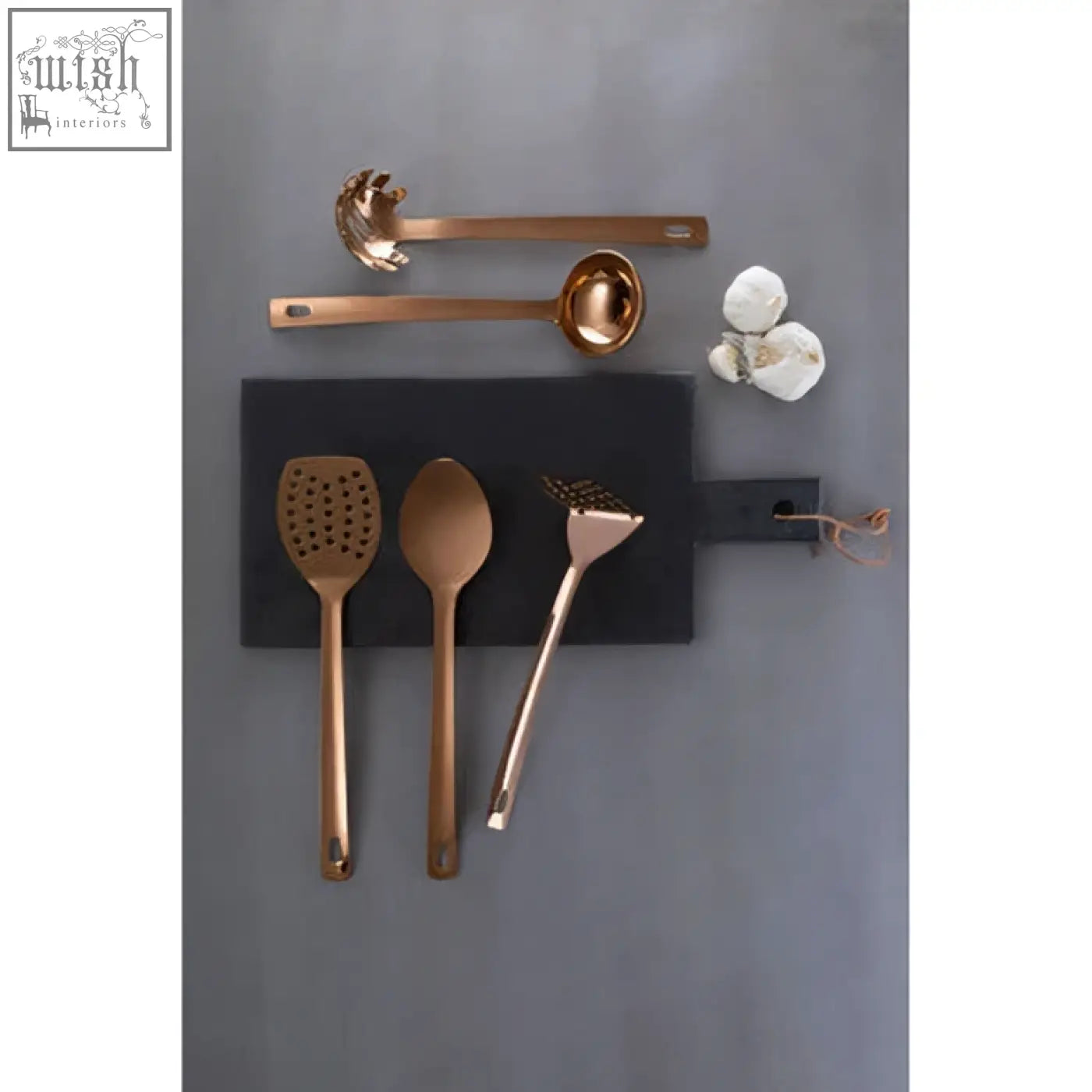 Set of rose gold finish kitchen utensils including ladle arranged on black cutting board for stylish cooking
