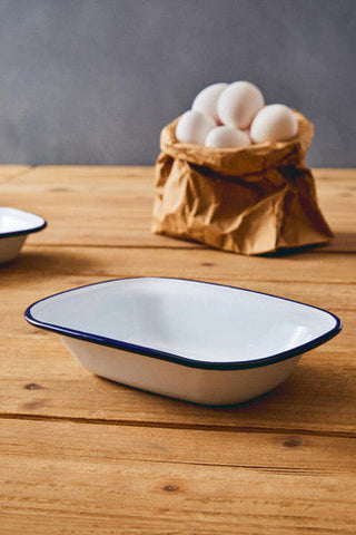 White enamel rectangular pie dish with navy blue rim from scratch 22cm resting on wooden surface
