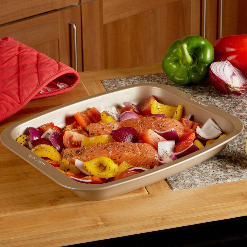Rectangular metallic from scratch 32cm roasting pan with seasoned salmon and colorful vegetables ready to cook