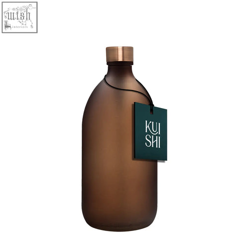 A sleek frosted amber glass bottle with a brushed steel cap and dark green kui shi logo tag