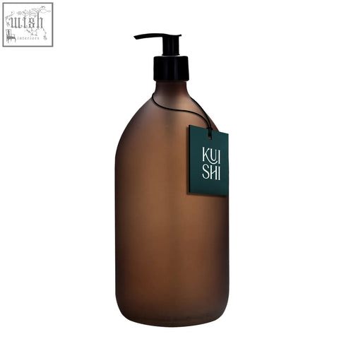 A sleek frosted amber glass pump bottle with black dispenser and kui shi dark green tag for stylish dispensing