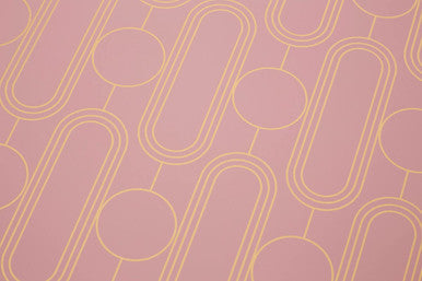 Pink placemats from the frosted deco set feature a repeating gold geometric oval and circle pattern for dining table use