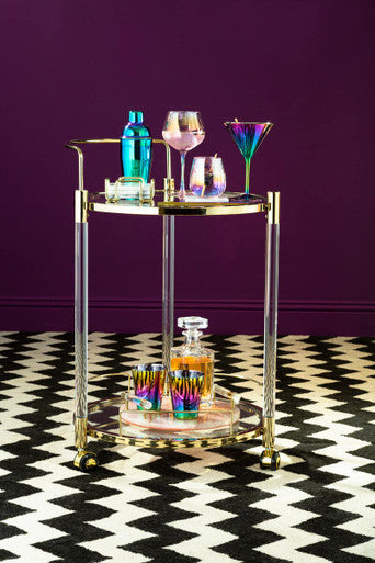 Gold-finished bar cart with clear acrylic shelves holding colorful frosted deco tumbler glasses from a deco set of 4