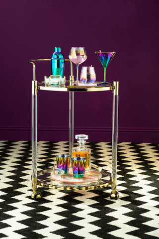 Gold-finished bar cart with clear acrylic shelves holding colorful frosted deco tumbler glasses from a deco set of 4