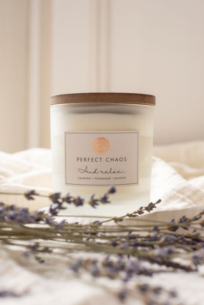 A frosted glass candle with wooden lid and perfect chaos and relax label offers long hours burn time on soft fabric