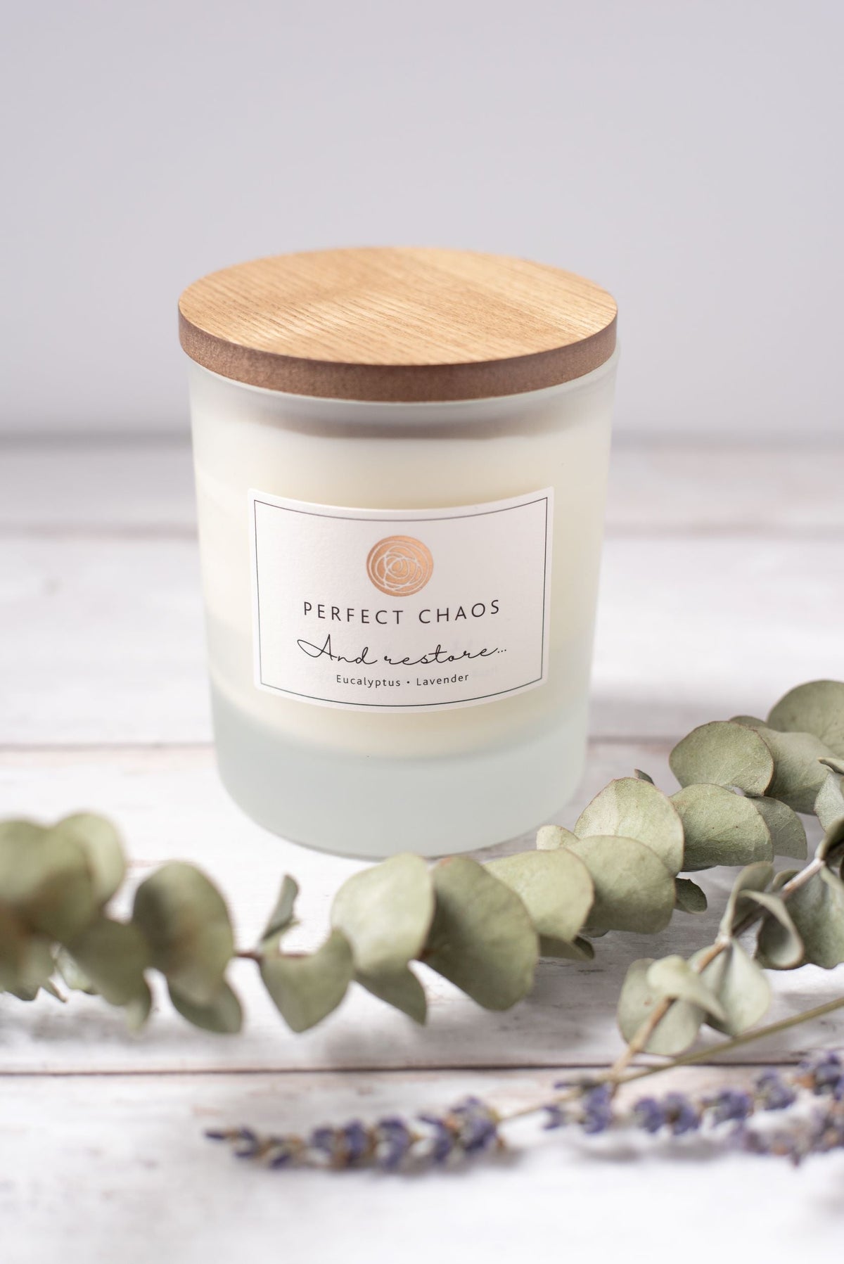 Frosted glass candle jar with wood lid featuring eucalyptus lavender essential oils and hours burn time label