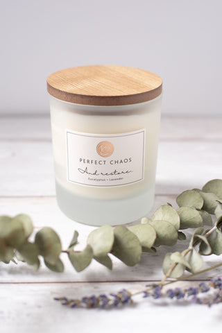 Frosted glass candle jar with wood lid featuring eucalyptus lavender essential oils and hours burn time label