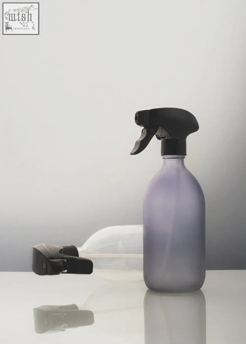 A frosted grey spray bottle with a translucent lavender body and black trigger pump for easy spraying