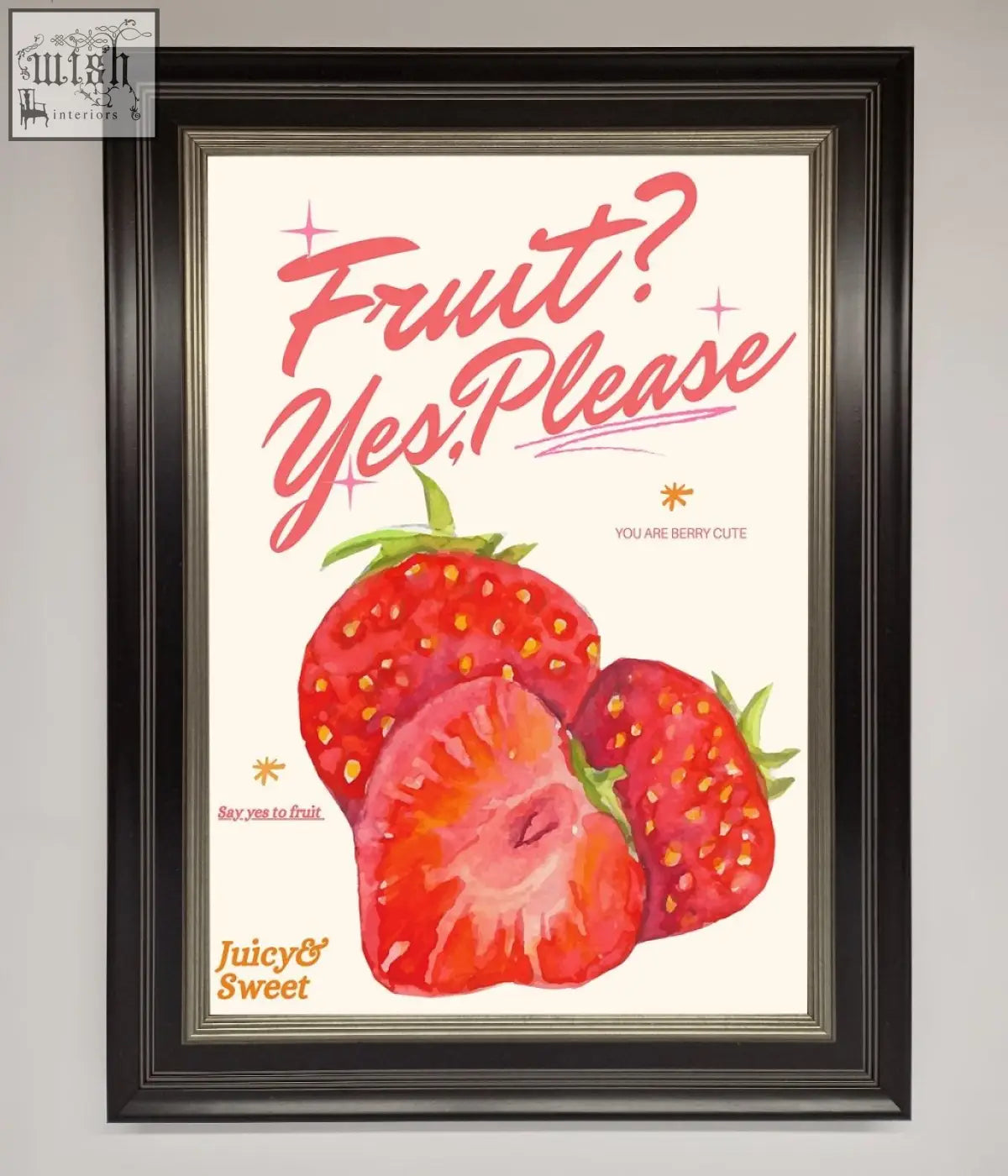 A framed poster with vibrant red strawberries and pink cursive fruit yes please text on a cream background