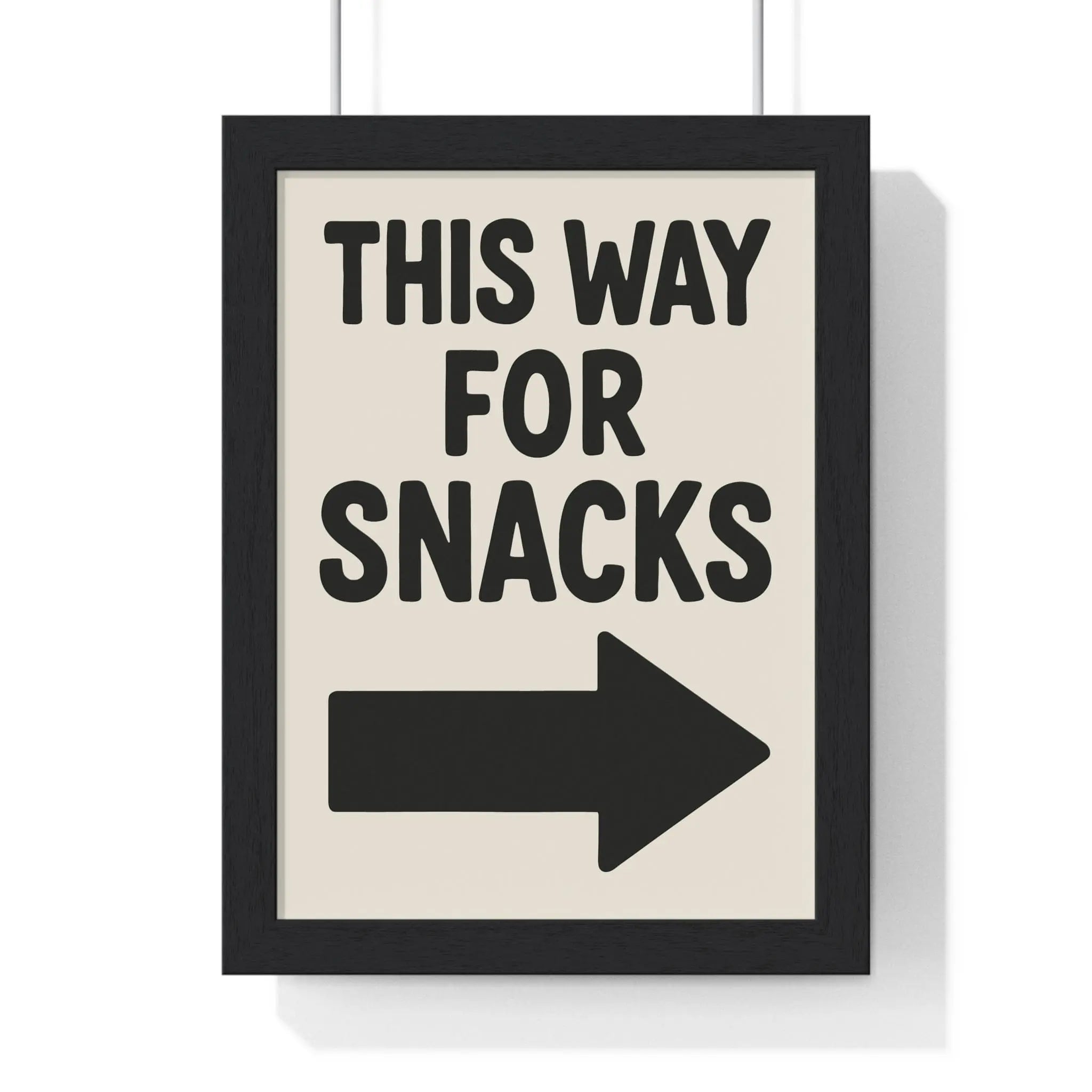 Black-framed funny kitchen poster with bold black text this way for snacks and right-pointing arrow on off-white background