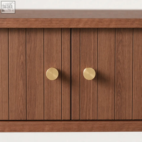 A pair of brushed brass knobs on a brown fluted console table with sliding tambour doors and storage shelf