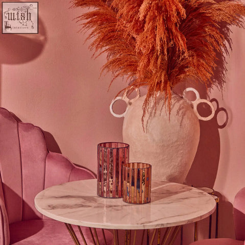 A pair of rose gold metallic gaia pink mosaic small candle holders with vertical stripes on a marble table