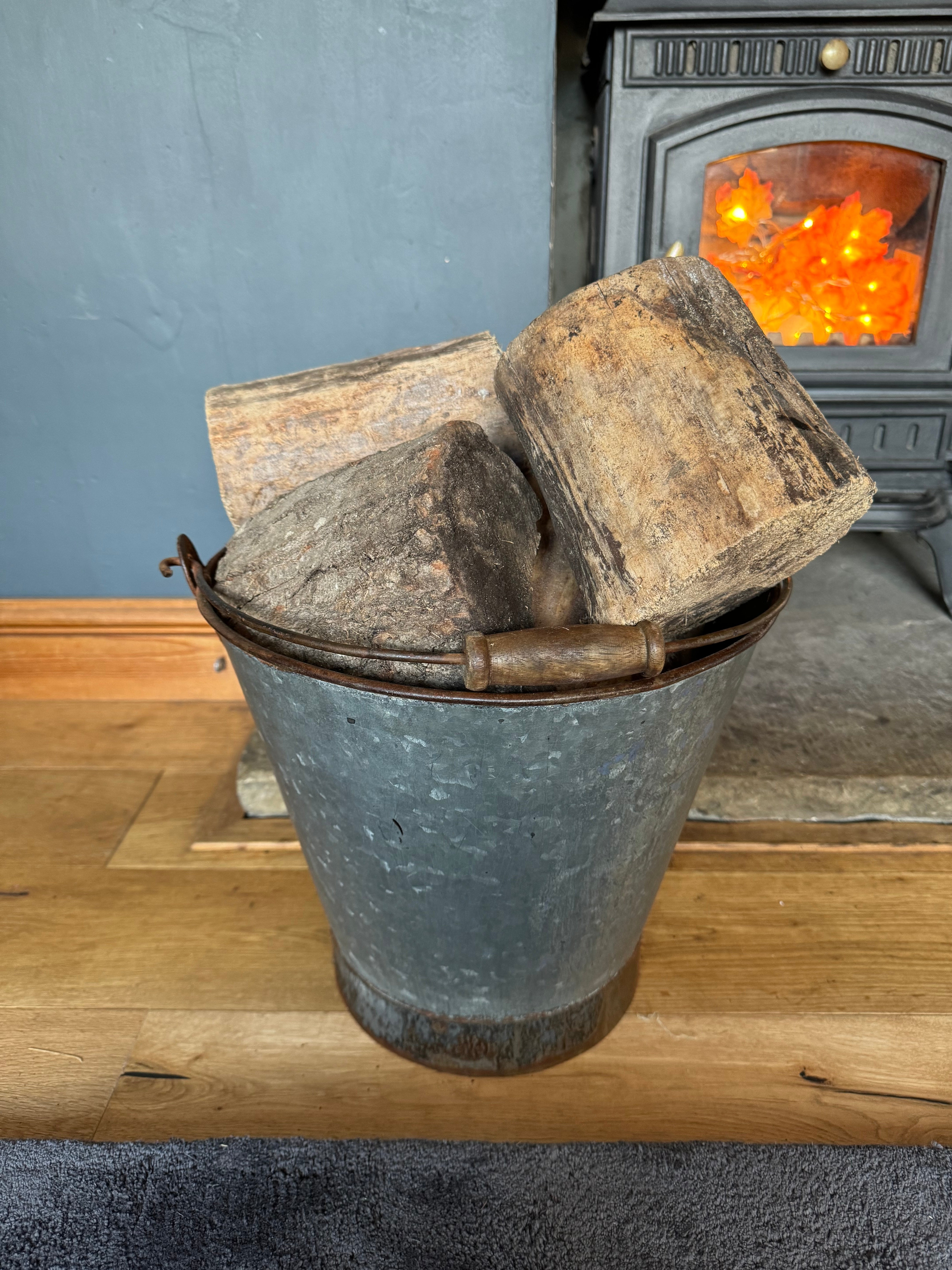 Galvanised metal log basket with wooden handle filled with rustic firewood for christmas tree planter or patio use