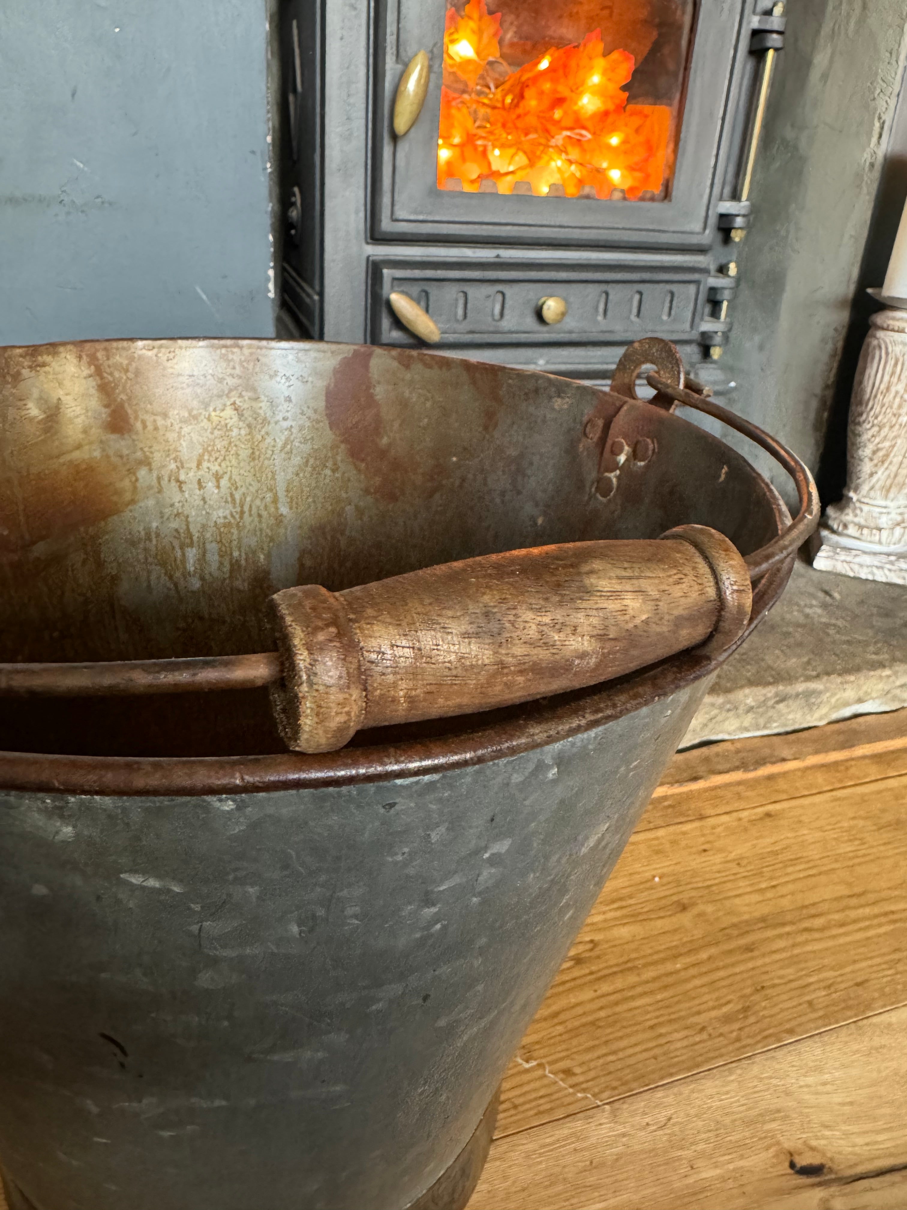 A rustic galvanized metal log basket with wooden handle perfect for holding firewood or a christmas tree on the patio