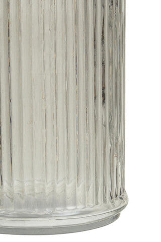 Clear glass lamp with vertical ridges and silver base next to garner glass storage jar with mango wood lid
