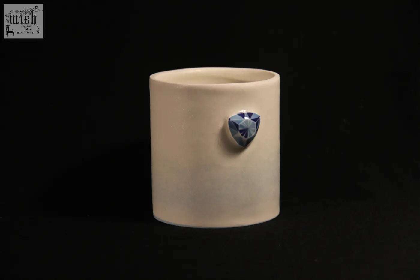 Cream-colored ceramic gem mug features five distinct sides with a faceted blue gemstone centerpiece