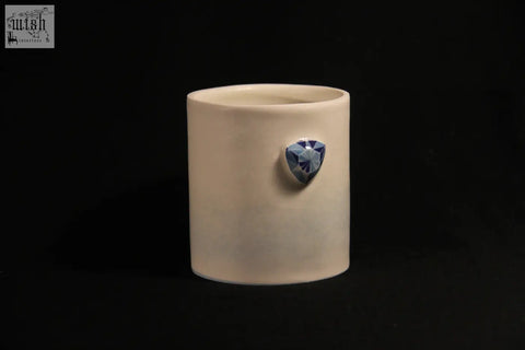 Cream-colored ceramic gem mug features five distinct sides with a faceted blue gemstone centerpiece