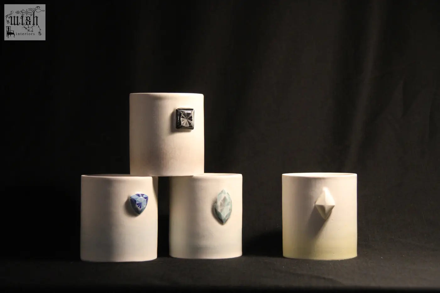 Cream-colored ceramic gem mug features five unique gemstone accents on cylindrical vases for stylish drinkware