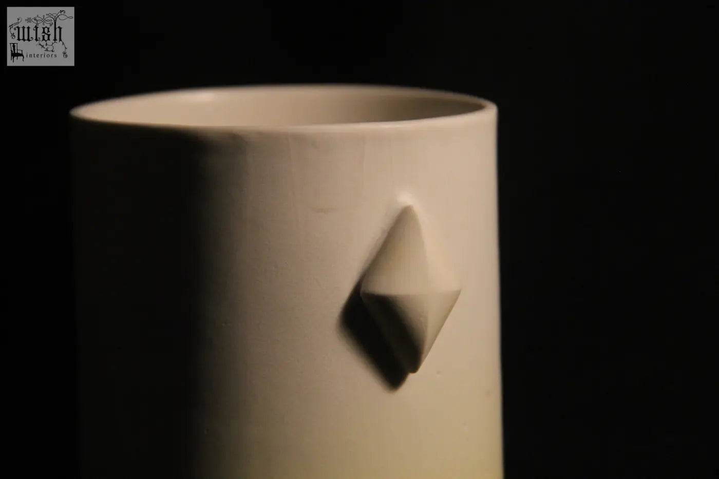 A minimalist white ceramic gem mug features five subtle geometric diamond-shaped reliefs on its side