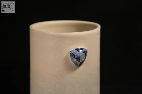 A sleek off-white ceramic gem mug features five with a single faceted blue gemstone on its side