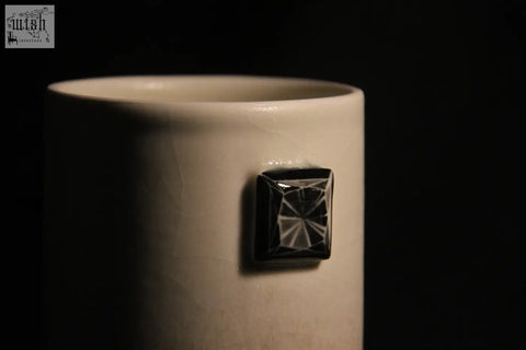 A white ceramic gem mug features five black faceted square accents on its side for a stylish look