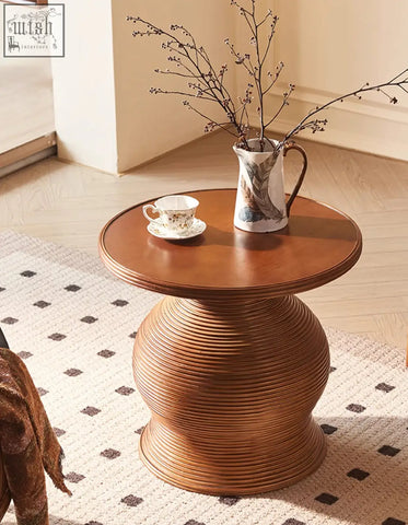 A round wooden side table with a ribbed textured base complements the gentry swivel rattan lounge chair shipping cost info included