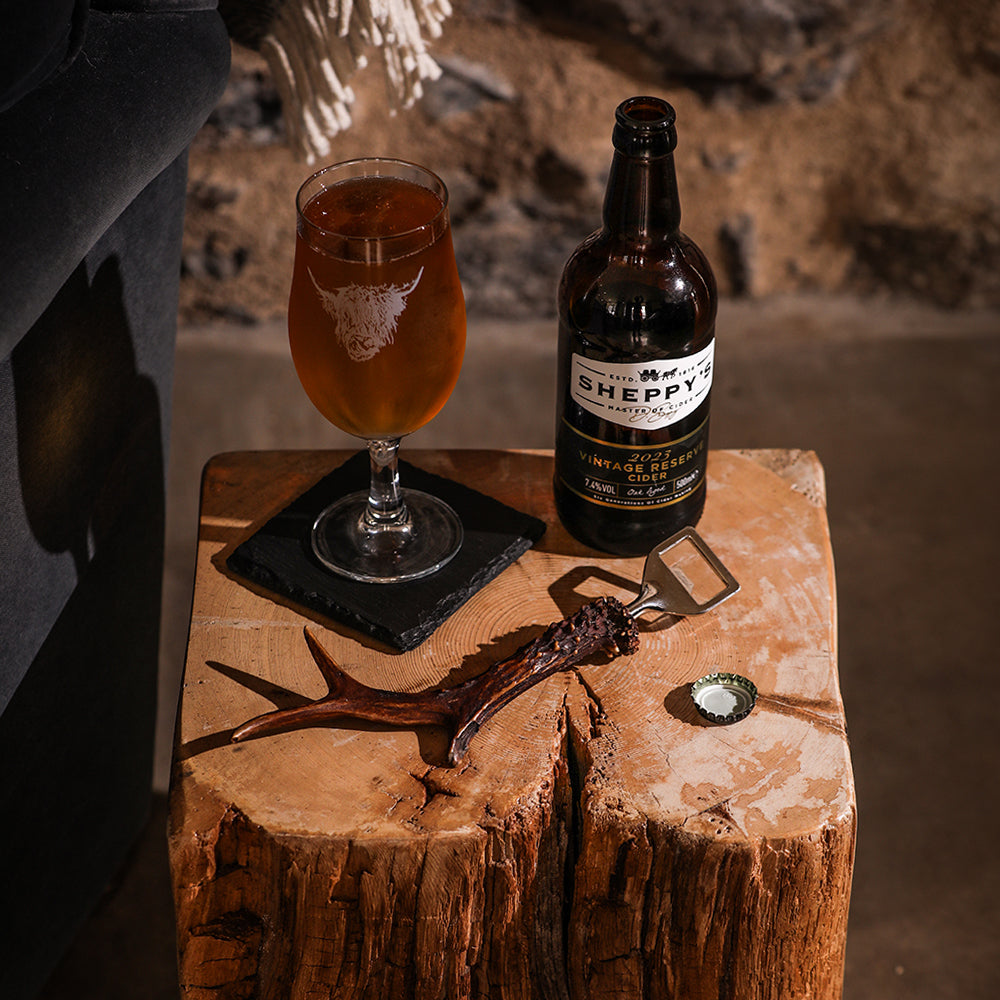 A dark brown bottle of sheppys 2021 vintage reserve cider with a white label featuring a genuine roe antler bottle opener