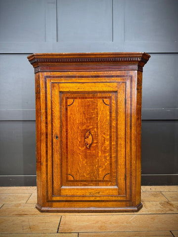 Genuine georgian oak corner cupboard with warm golden brown finish and intricate inlaid woodwork on the door