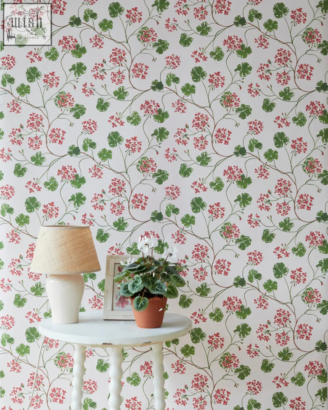 A white ceramic table lamp with a beige woven shade adds mediterranean charm to geraniums wallpaper decor
