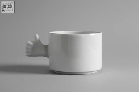 White ceramic mug with a sculpted thumb up hand handle from 4am product design cups series porcelain coffee cup