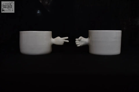White ceramic gesture cups with sculpted hands showing peace sign and fist handmade porcelain 4am product design