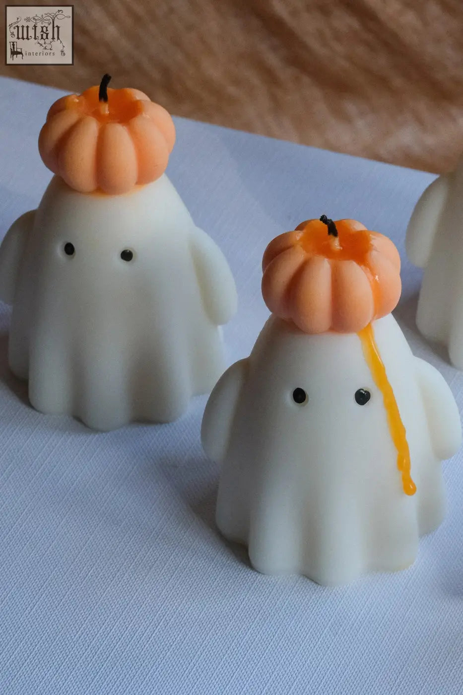 White ghost candle with natural soy wax featuring orange pumpkin hat and black dot eyes for halloween decor