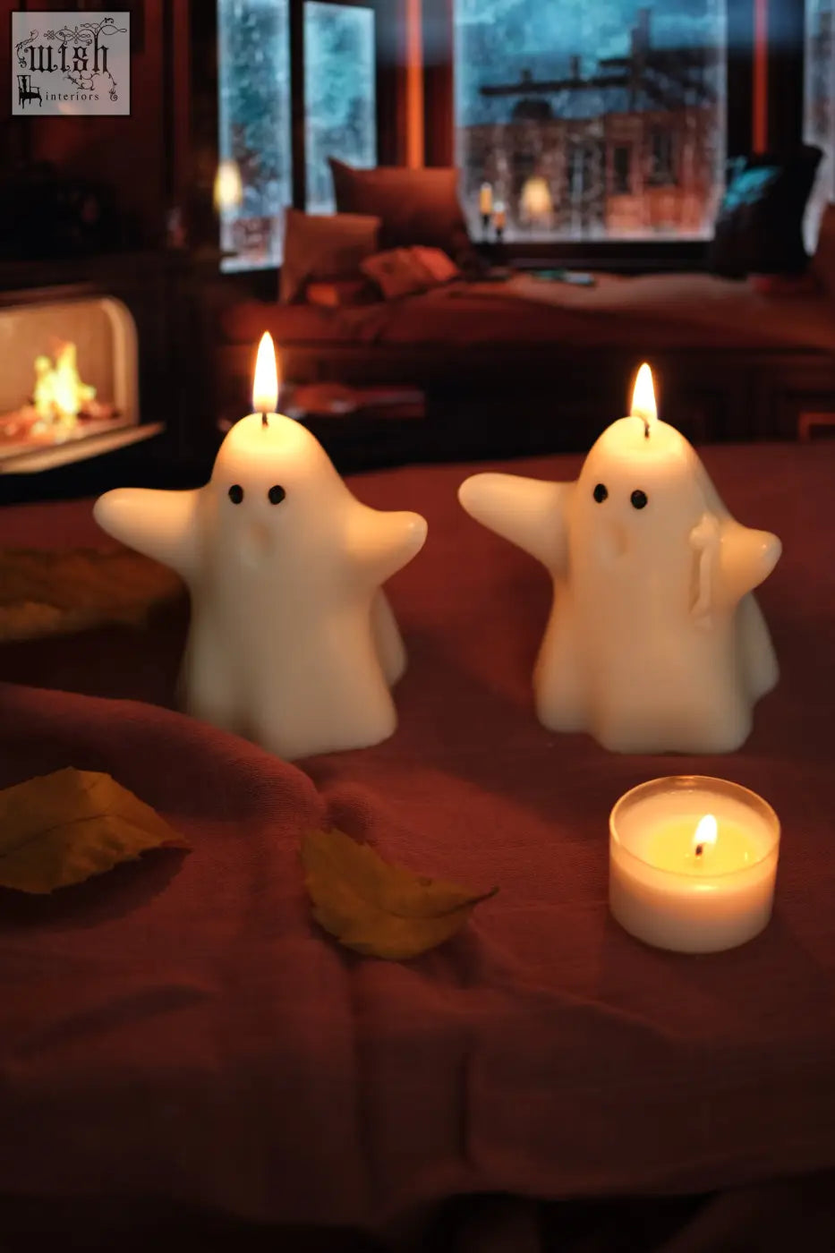 Two white ghost candles with black eyes and lit wicks perfect for pumpkin spiced halloween vibes and cozy spiced latte nights