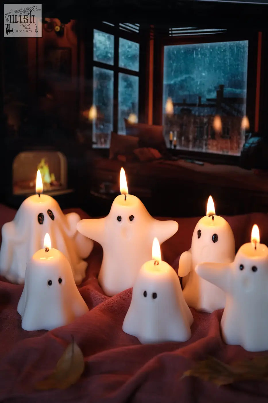 White ghost-shaped halloween candles with lit wicks on red fabric perfect for pumpkin spiced vibes and spiced latte mood