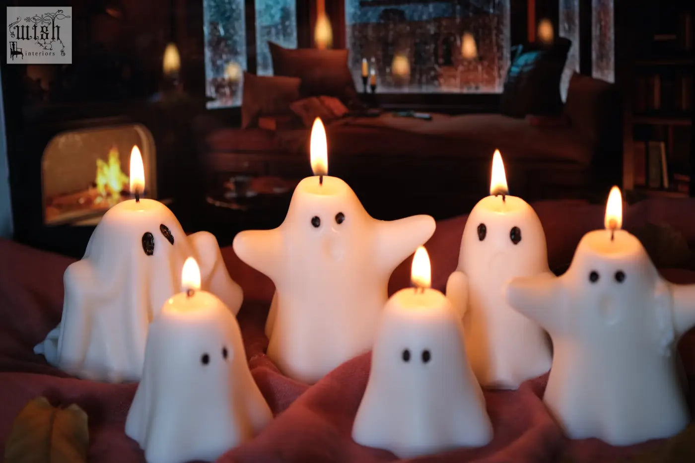 White ghost-shaped halloween candles with lit wicks on red fabric perfect for pumpkin spiced halloween vibes