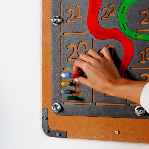Giant snakes and ladders game board with a colorful tactile number puzzle on gray surface and brown wooden frame