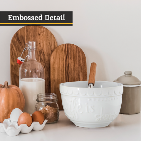 White set of two mixing bowls featuring a ceramic bowl with embossed floral pattern and wooden handle whisk inside