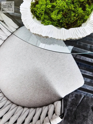 Grey dining chair with woven back shown with gray textured cushion and white ceramic bowl filled with green moss on top