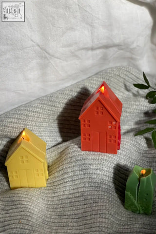 Red plastic gingerbread house candle with glowing flame from the gingerbread house candles trio set