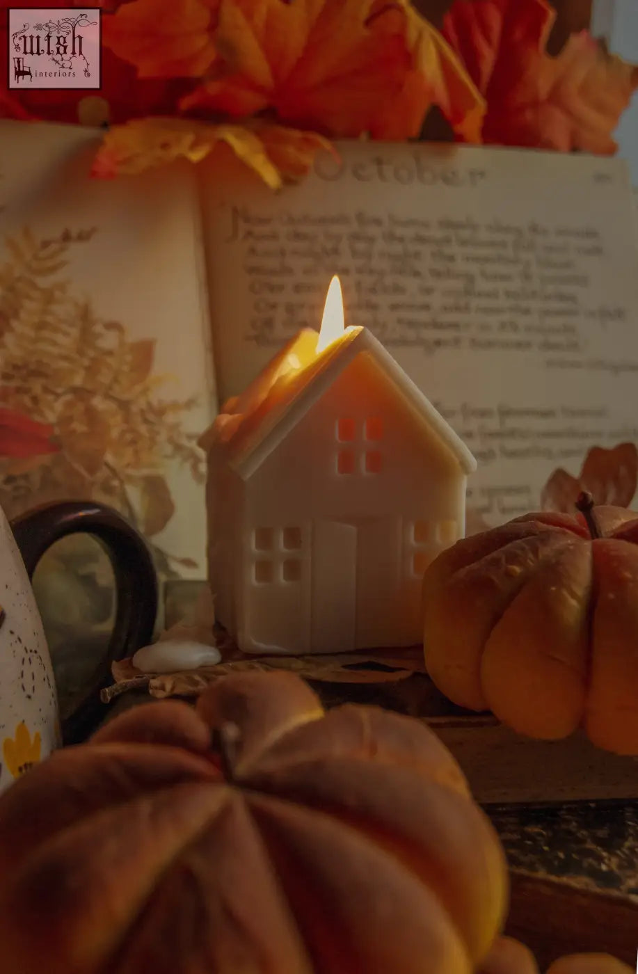 A warm glowing white gingerbread house candle with lit wick and cut-out windows perfect for cozy decor