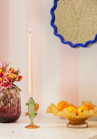 Ginny’s glass bass candle holder is a translucent green glass fish with orange fins on an ornate gold base