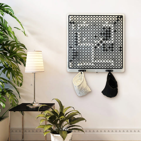 Black and white hexagonal mesh wall organizer with two hooks holding a cap and bag for go strategy wall game with hanging instructions