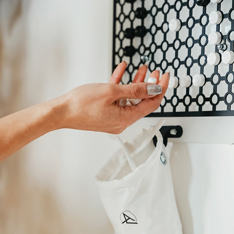 White fabric tote bag with minimalist black logo embroidered near bottom perfect for shuffle board and easy hanging instructions