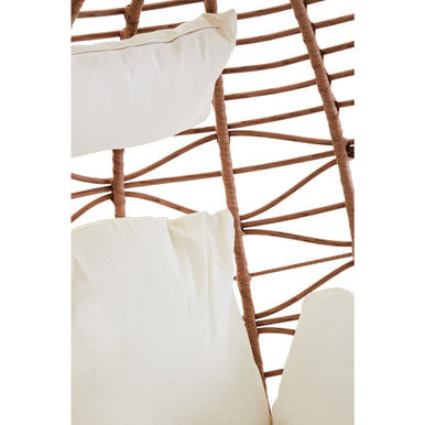 White cushioned pillows rest against a natural rattan effect brown woven frame in the goa hanging chair