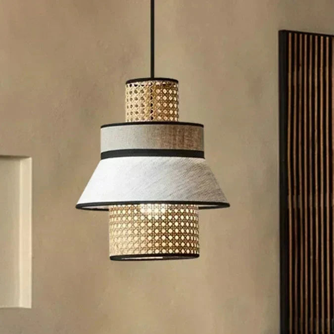 A tiered pendant light called gokna light with woven rattan and textured white fabric shades accented by black trim