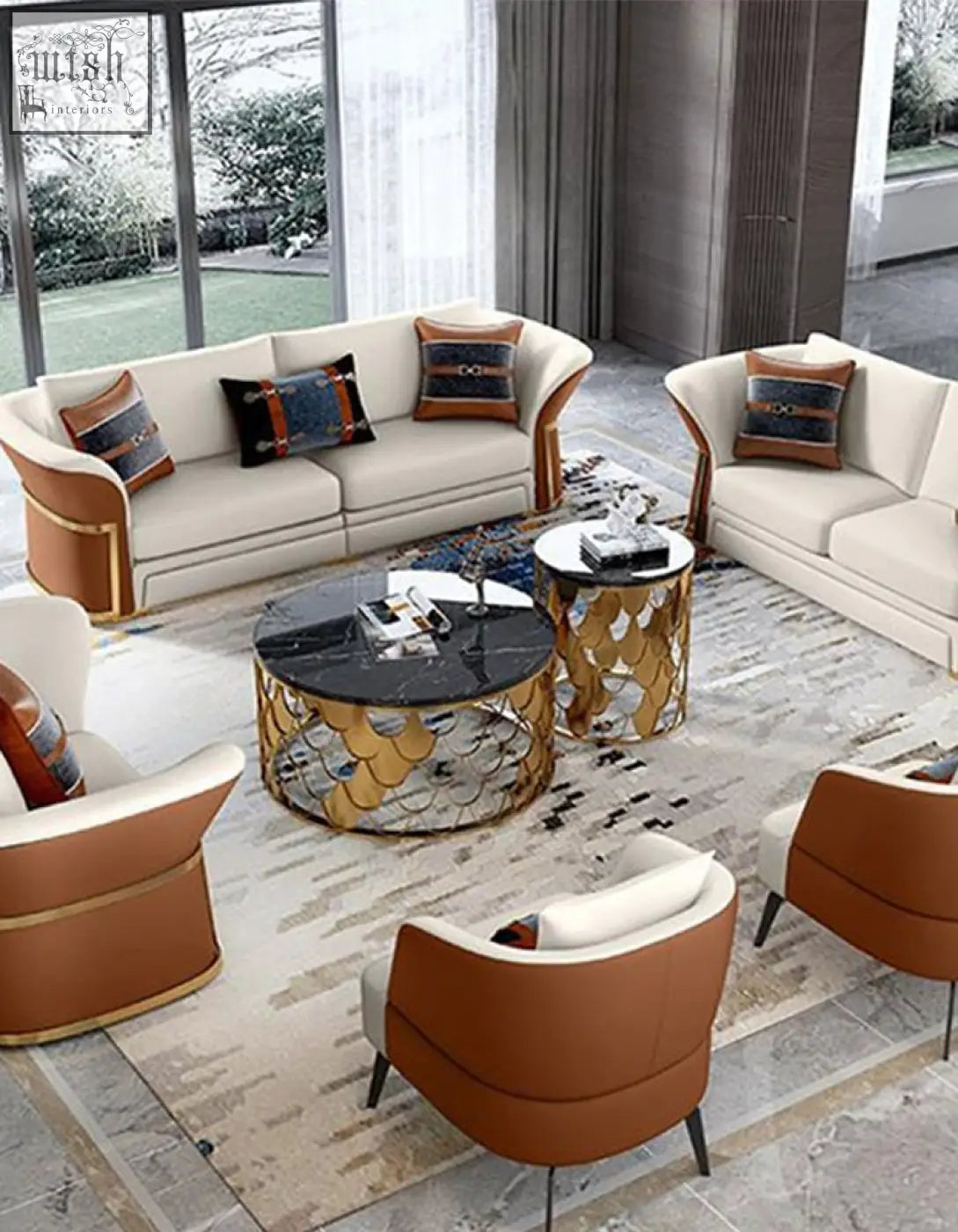 Cream-colored leather sofa with gold-trimmed arms and pillows beside a gold nesting coffee table with marble top