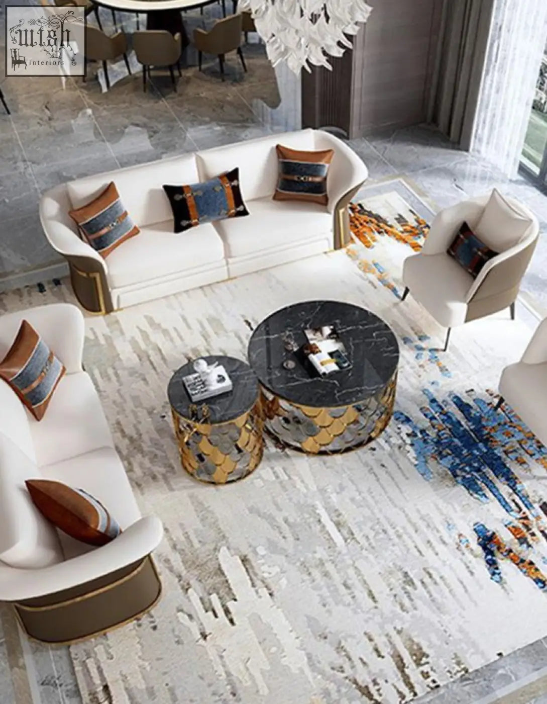 White sofa with gold trim and patterned pillows beside a gold nesting coffee table with marble top