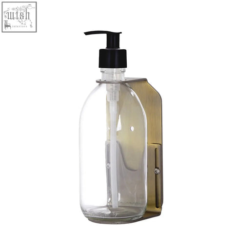 Clear glass soap dispenser with black pump and gold wall-mounted brass bracket for bathroom or kitchen use