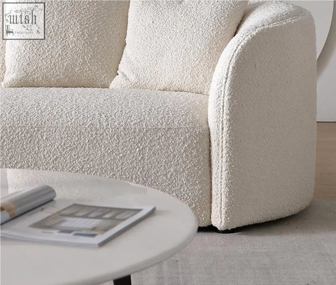 Cream-colored plush boucle three seater sofa with rounded armrests and cushions goldie gubi three seater